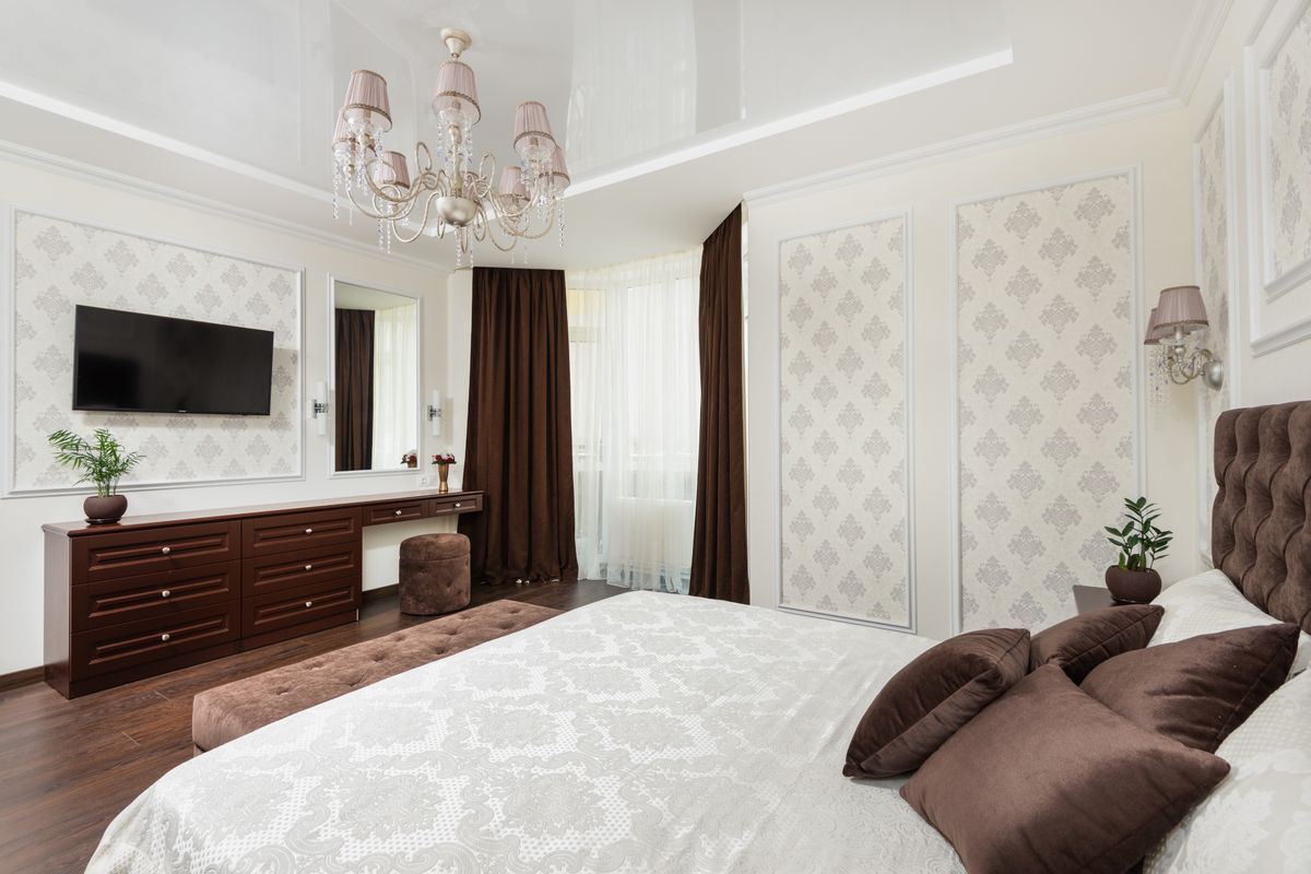 A beautifully layered bed with white fitted and flat sheets, a folded grey duvet at the foot, and a textured throw blanket draped across the corner in soft morning light